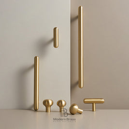 A set of modern brass cabinet knobs in various shapes and sizes, including long bar handles, round ball knobs, and T-bar handles, displayed on a light beige surface against a matching beige background. The brand logo 'Modern Brass Home Hardware' is visible at the bottom.