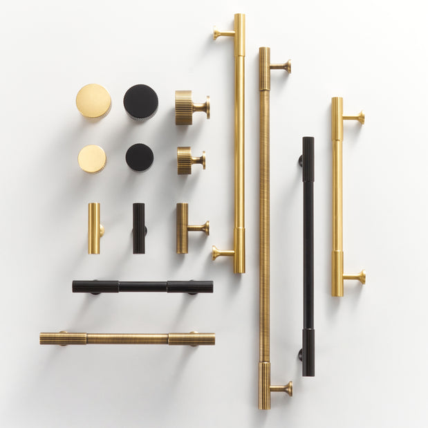Collection of gold, black, and bronze door handles and knobs on a white background