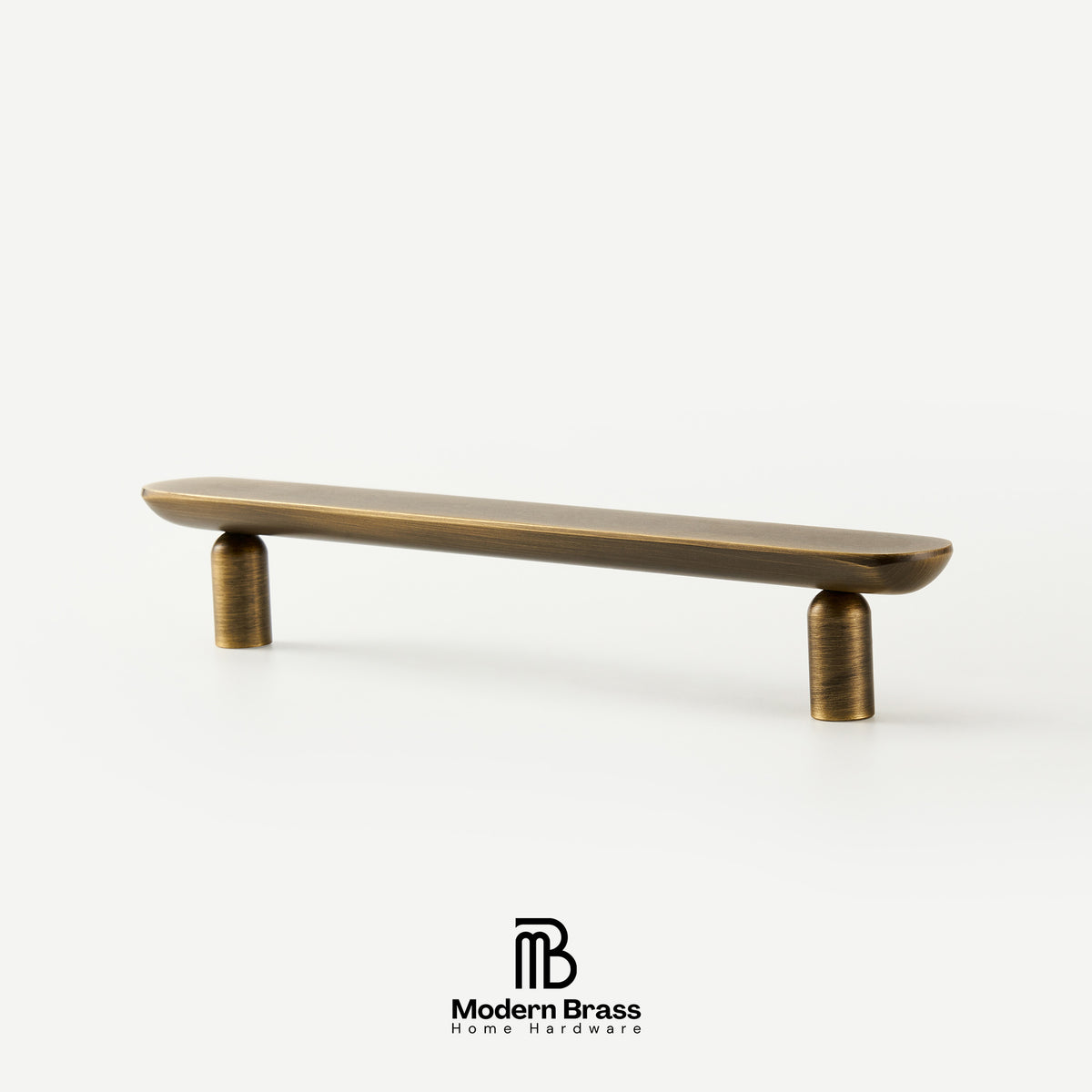 Three round cabinet knobs in black, matte brass, and brushed brass are arranged on a light beige surface against a warm beige background. The Modern Brass logo is visible at the bottom.