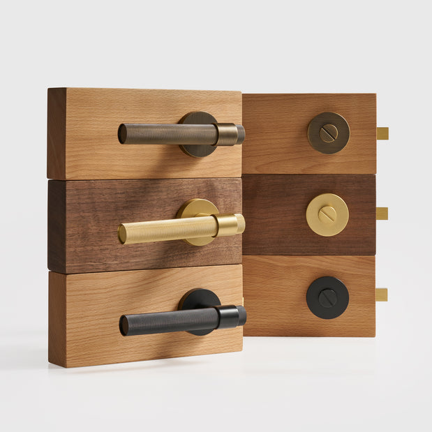 Wooden door handles and locks with brass and black finishes on a white background