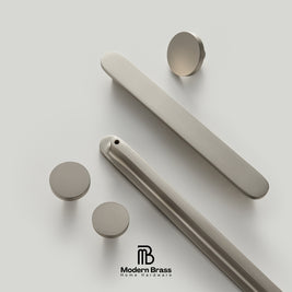 Set of beige door handles and knobs on a light gray background with 'Modern Brass' branding.