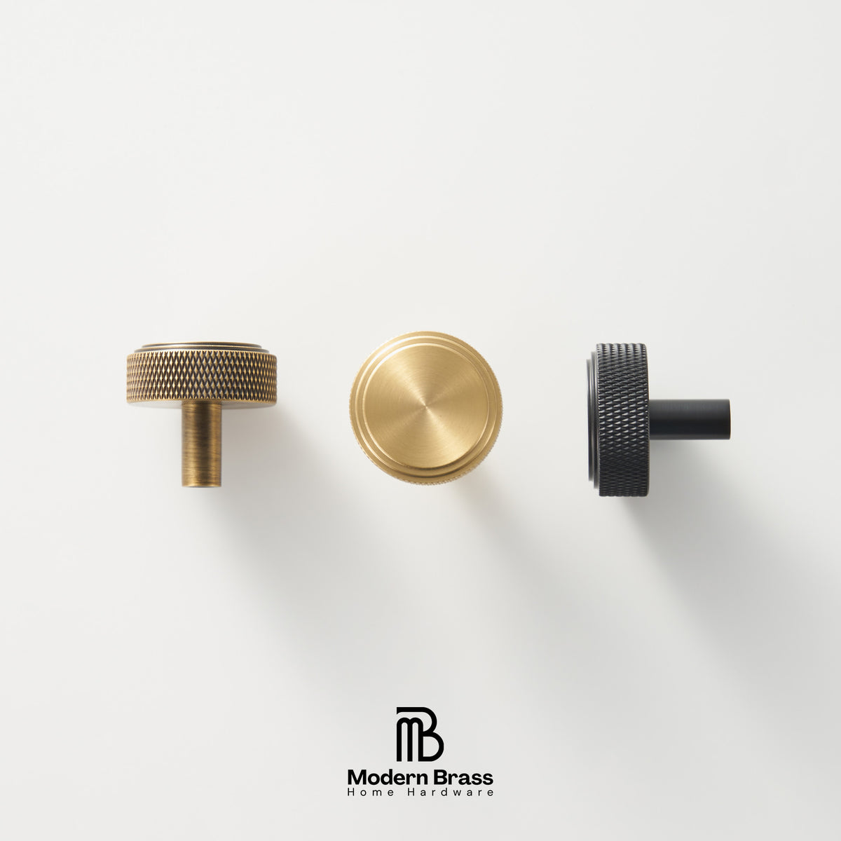 Three round cabinet knobs in black, matte brass, and brushed brass are arranged on a light beige surface against a warm beige background. The Modern Brass logo is visible at the bottom.