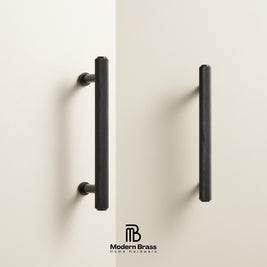 Two modern vertical cabinet handles in a textured matte black finish, mounted on a clean off-white wall. The Modern Brass Home Hardware logo is visible at the bottom center.
