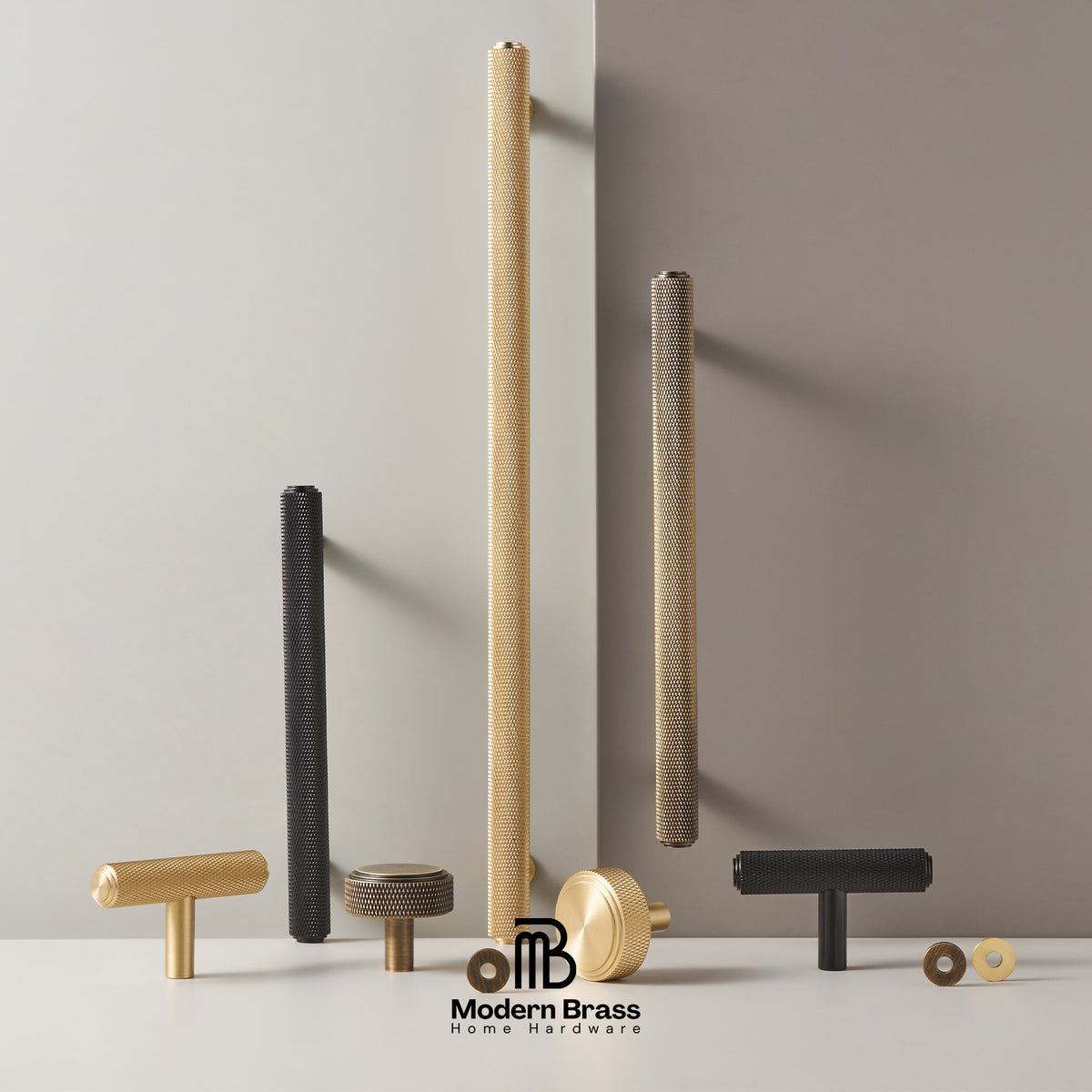 A collection of modern brass and black metal cabinet hardware, including textured vertical bar pulls, T-bar pulls, and round knobs, displayed on a white surface against a split beige and gray background. The Modern Brass logo is visible at the bottom.