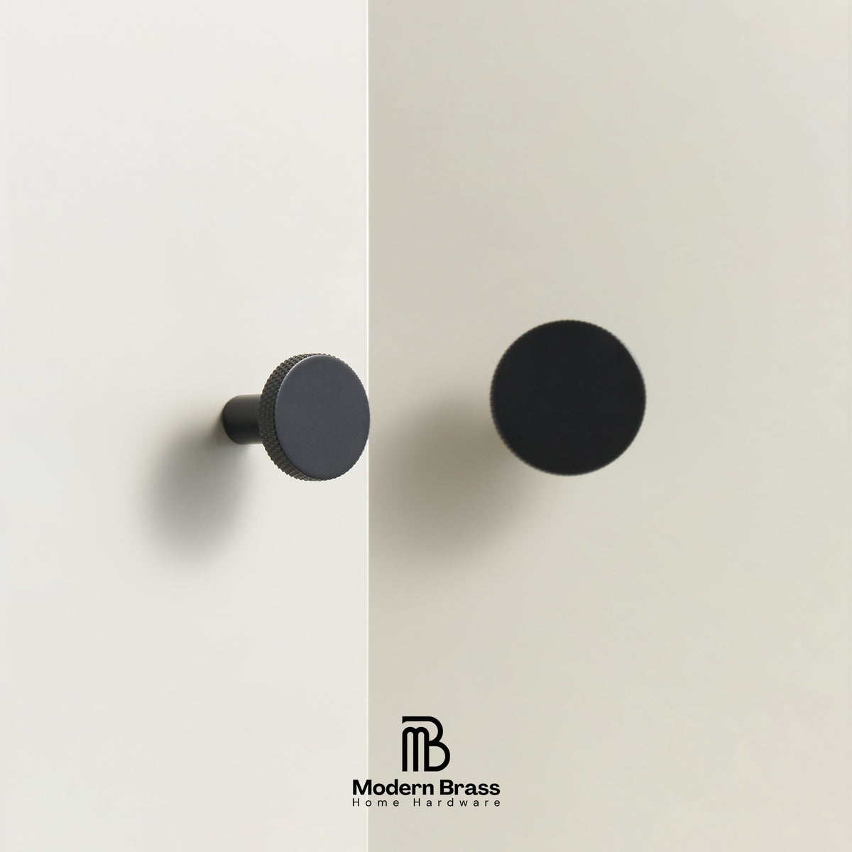 Two round cabinet knobs in matte black finishes shown mounted on a light beige wall, with the Modern Brass Home Hardware logo at the bottom.
