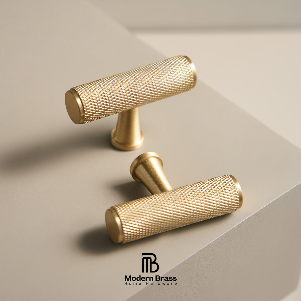 Three round cabinet knobs in black, matte brass, and brushed brass are arranged on a light beige surface against a warm beige background. The Modern Brass logo is visible at the bottom.