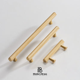 Three brass cabinet knobs in different sizes arranged diagonally on a light gray background, with the Modern Brass logo at the bottom.