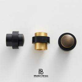 Three modern brass home hardware knobs in black and brushed gold finishes, displayed on a clean white background with the Modern Brass logo at the bottom.