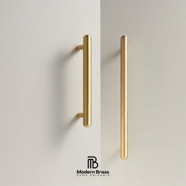 Two slim vertical brass cabinet handles mounted on a light beige wall, with a Modern Brass logo at the bottom.
