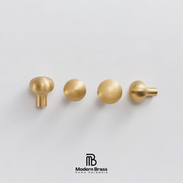 Four brass cabinet knobs in different shapes arranged horizontally on a light gray background, with the Modern Brass Home Hardware logo at the bottom.