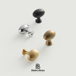 Three round cabinet knobs in black, matte brass, and brushed brass are arranged on a light beige surface against a warm beige background. The Modern Brass logo is visible at the bottom.