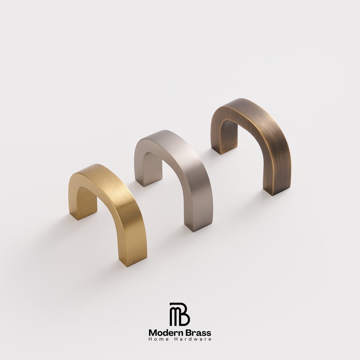 Three modern arched cabinet pulls in brushed brass, satin nickel, and oil-rubbed brown, arranged diagonally on a light gray background with the Modern Brass Home Hardware logo at the bottom.
