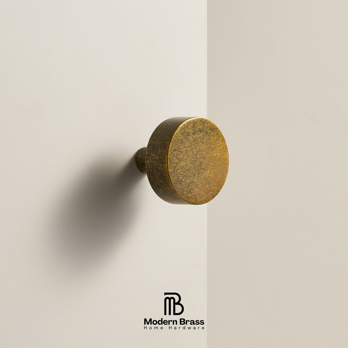 Three round cabinet knobs in black, matte black, and brushed brass are displayed on a light beige surface against a warm beige background. The Modern Brass logo is visible at the bottom.