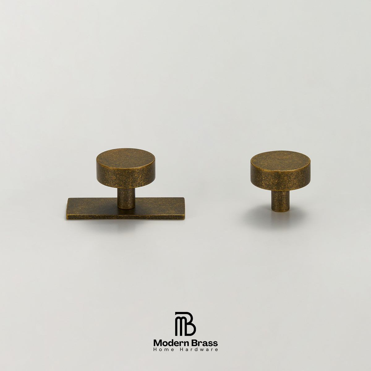 Two brass cabinet knobs in an antique bronze finish, one rectangular with a round top and one round with a short post, displayed on a light gray background with the Modern Brass logo at the bottom.