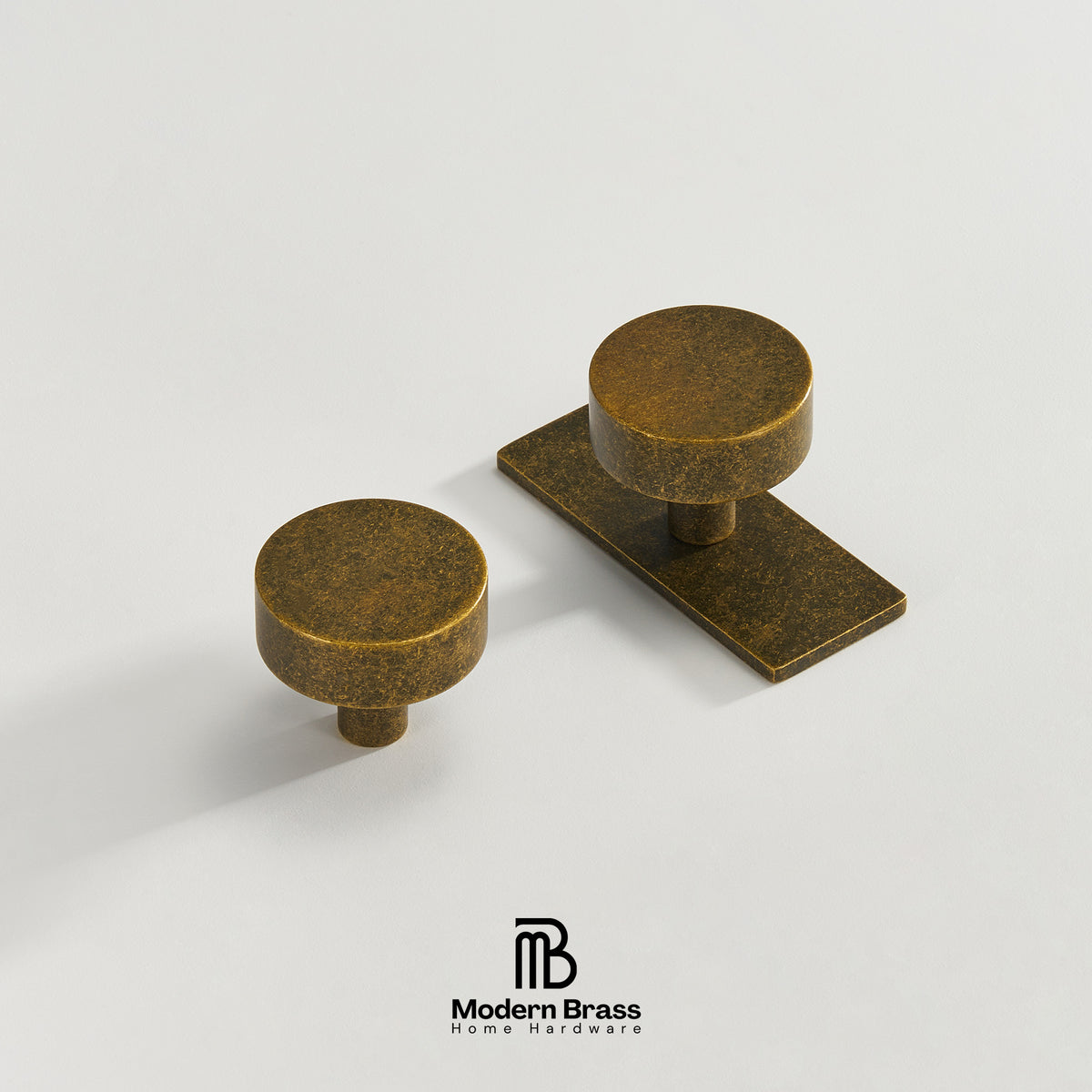 Two round brass cabinet knobs with a textured antique finish, one single knob and one matching knob mounted on a rectangular base, shown on a light gray background with the Modern Brass logo at the bottom.