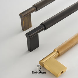 Three modern cabinet pull handles with knurled textured shafts and square block bases, shown in black, dark bronze, and gold finishes on a light gray background. The Modern Brass logo is visible at the bottom.
