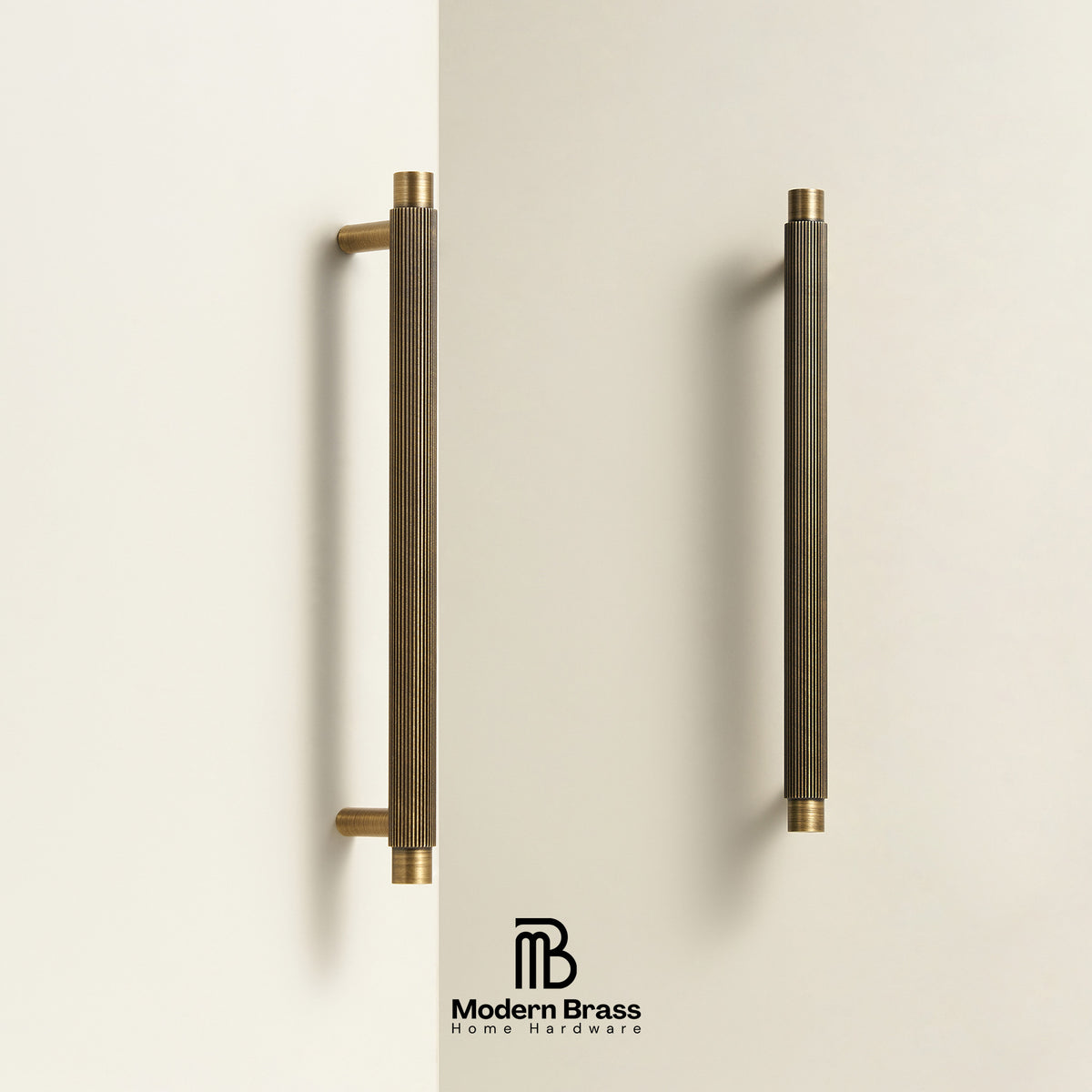 Two long cylindrical cabinet handles in a brushed brass finish with gold-toned end caps, mounted on a light beige wall. The Modern Brass logo is visible at the bottom.