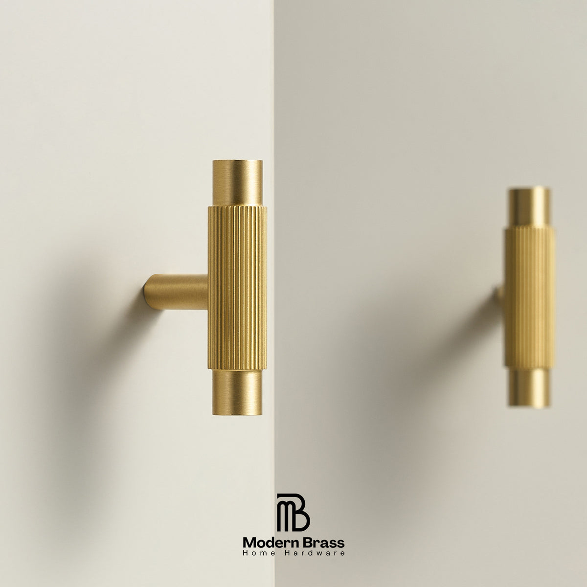 Two modern vertical wall-mounted brass handles with a ribbed cylindrical design, shown on a clean off-white wall with a soft shadow. The brand logo 'Modern Brass Home Hardware' is visible at the bottom.