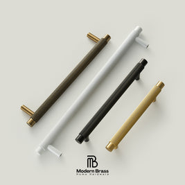 Four modern cylindrical cabinet handles in dark bronze, white, black, and gold finishes, arranged diagonally on a light beige background with the Modern Brass logo at the bottom.