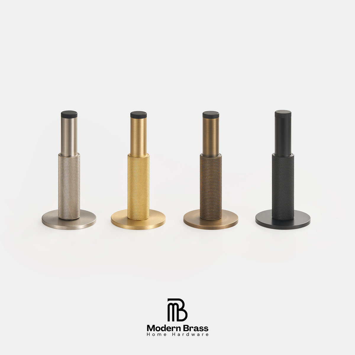 Four modern brass wall anchors in different finishes (silver, gold, bronze, and black) arranged in a row on a light gray background, with the Modern Brass logo at the bottom.