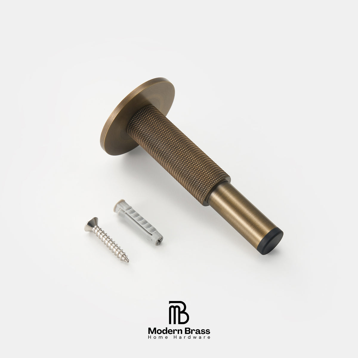 An antique brass door pull handle with a knurled grip and a flat round backplate, shown with a mounting screw and wall anchor on a clean white background. The Modern Brass logo is visible at the bottom.