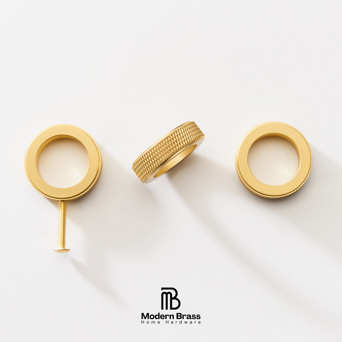 Three gold-finished brass hardware components, including two circular ring-shaped pieces and a textured cylindrical piece with a screw, arranged on a clean white background. The Modern Brass logo is visible at the bottom.