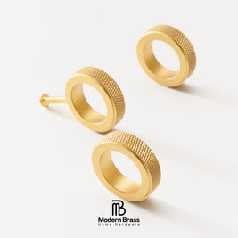 Four-piece brass cabinet hardware set including two long vertical bar handles, one short vertical bar handle, one horizontal pull handle, and three round cabinet knobs, displayed on a white surface against a beige background. The Modern Brass logo is visible at the bottom.