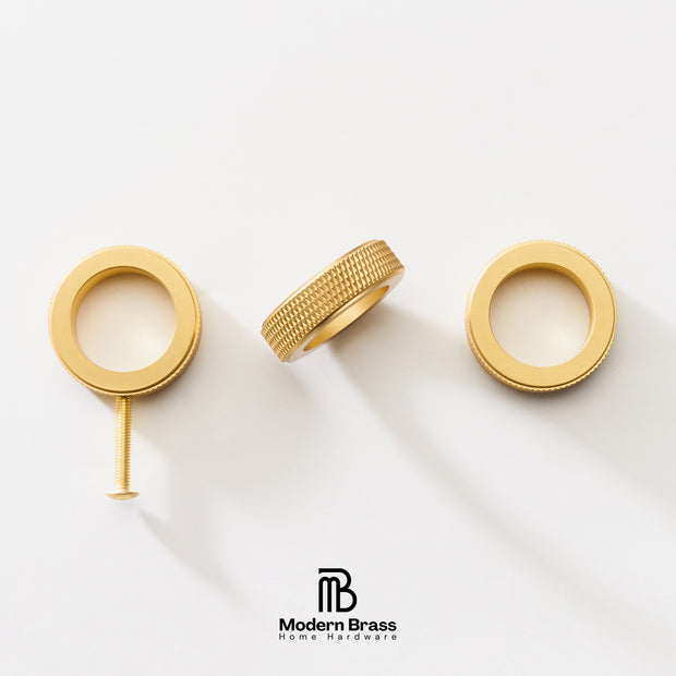 Three gold-finished brass hardware components, including two circular ring-shaped pieces and a textured cylindrical piece with a screw, arranged on a clean white background. The Modern Brass logo is visible at the bottom.