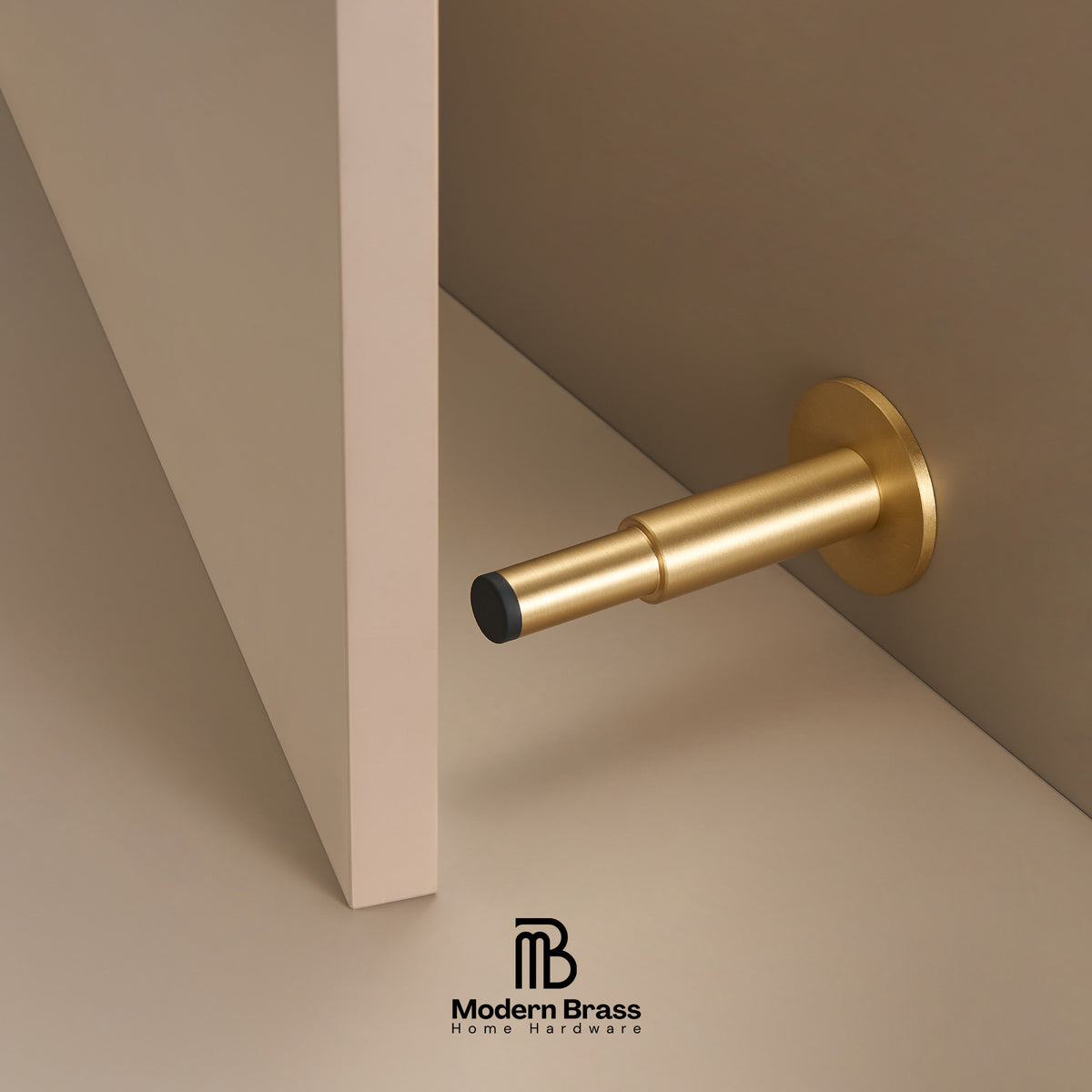 Three round cabinet knobs in black, matte brass, and brushed brass are arranged on a light beige surface against a warm beige background. The Modern Brass logo is visible at the bottom.