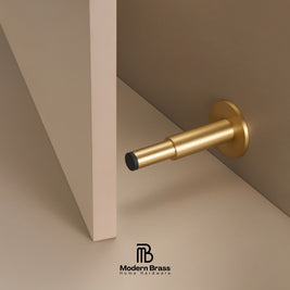Three round cabinet knobs in black, matte brass, and brushed brass are arranged on a light beige surface against a warm beige background. The Modern Brass logo is visible at the bottom.