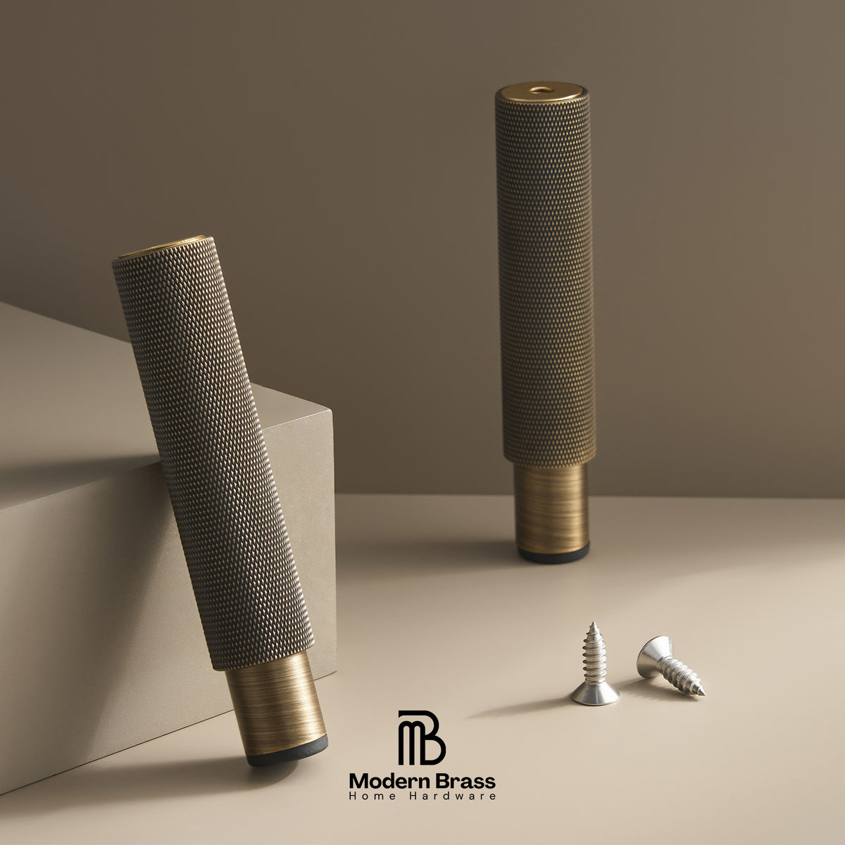 Two cylindrical brass home hardware pieces with textured mesh bodies and polished brass ends, displayed on a beige surface with two silver screws. The Modern Brass Home Hardware logo is visible at the bottom.