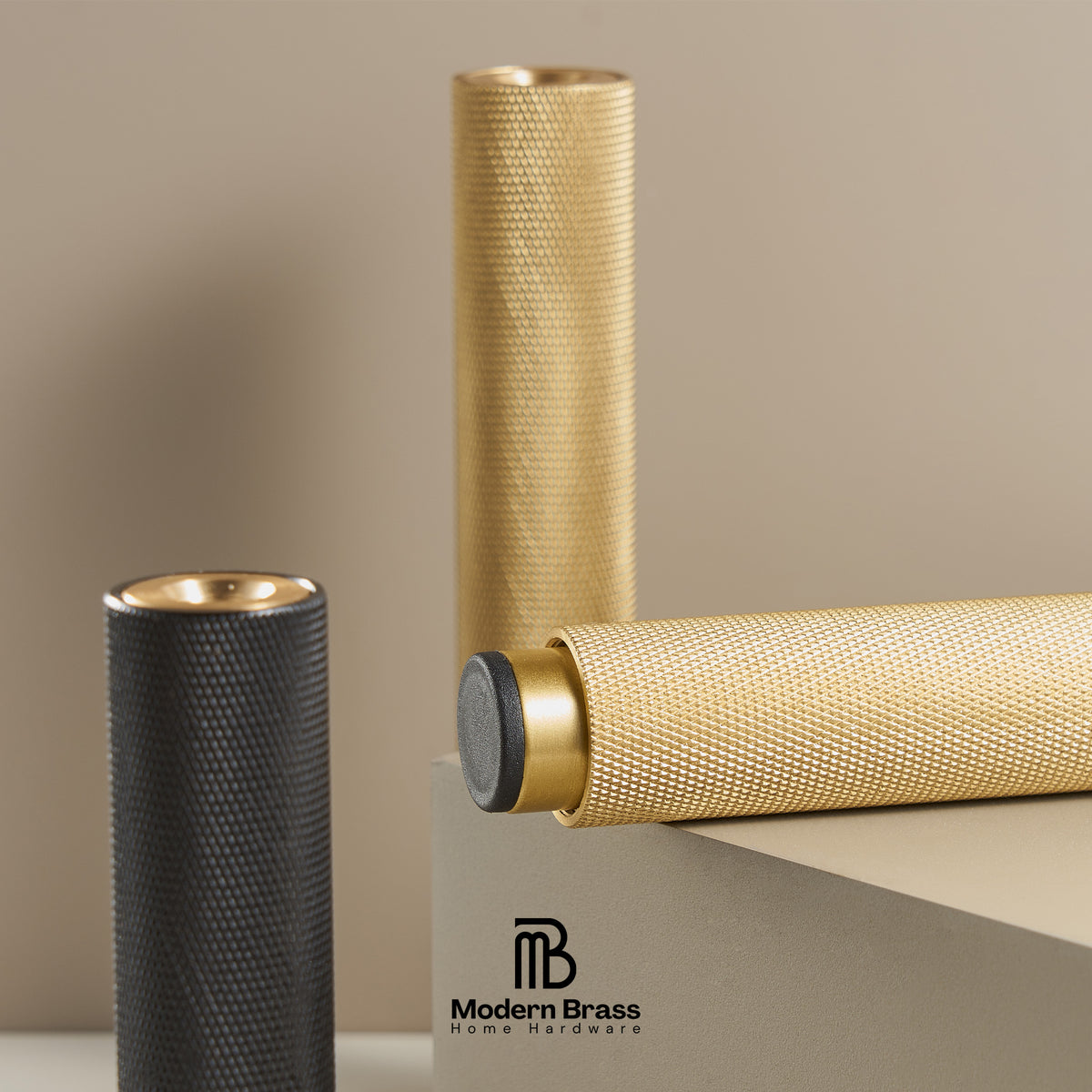 Two cylindrical textured brass home decor pieces, one gold and one dark gray, displayed on a neutral beige background with a Modern Brass logo at the bottom.