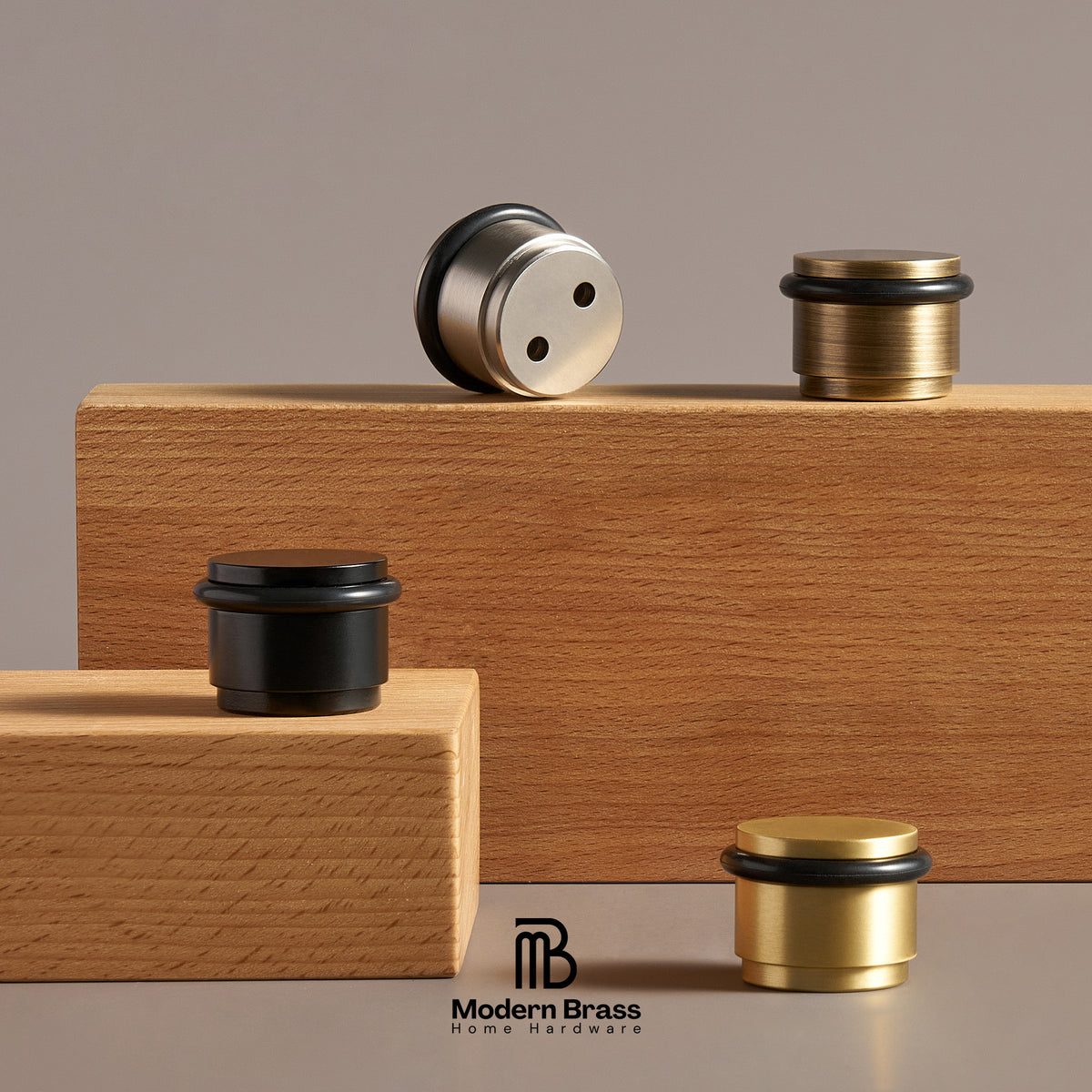 Four brass and stainless steel home barware pieces displayed on wooden blocks against a warm gray studio background. The Modern Brass logo appears at the bottom center.