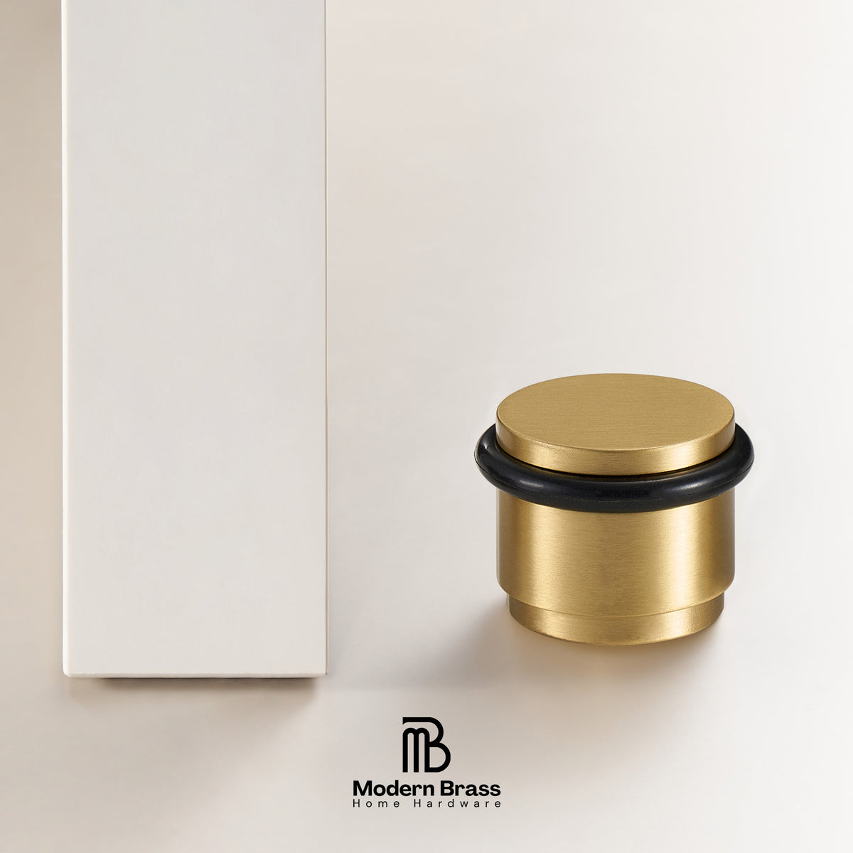 A brushed brass home hardware component with a black rubber O-ring and a matching round lid, shown next to a white rectangular box on a light beige background. The Modern Brass logo is visible at the bottom.