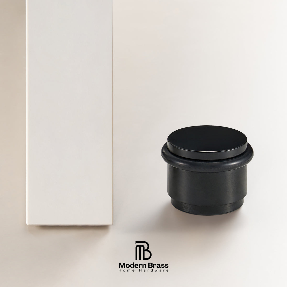 Top-down view of antique bronze smooth solid brass door stop showing brushed circular top face and black rubber ring

Side profile of matte black smooth