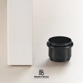Top-down view of antique bronze smooth solid brass door stop showing brushed circular top face and black rubber ring

Side profile of matte black smooth