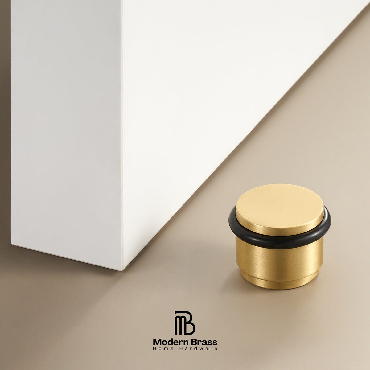 A small round brass cabinet pull handle with a black rubber gasket, shown on a beige surface next to a white cabinet corner. The Modern Brass logo is visible at the bottom.