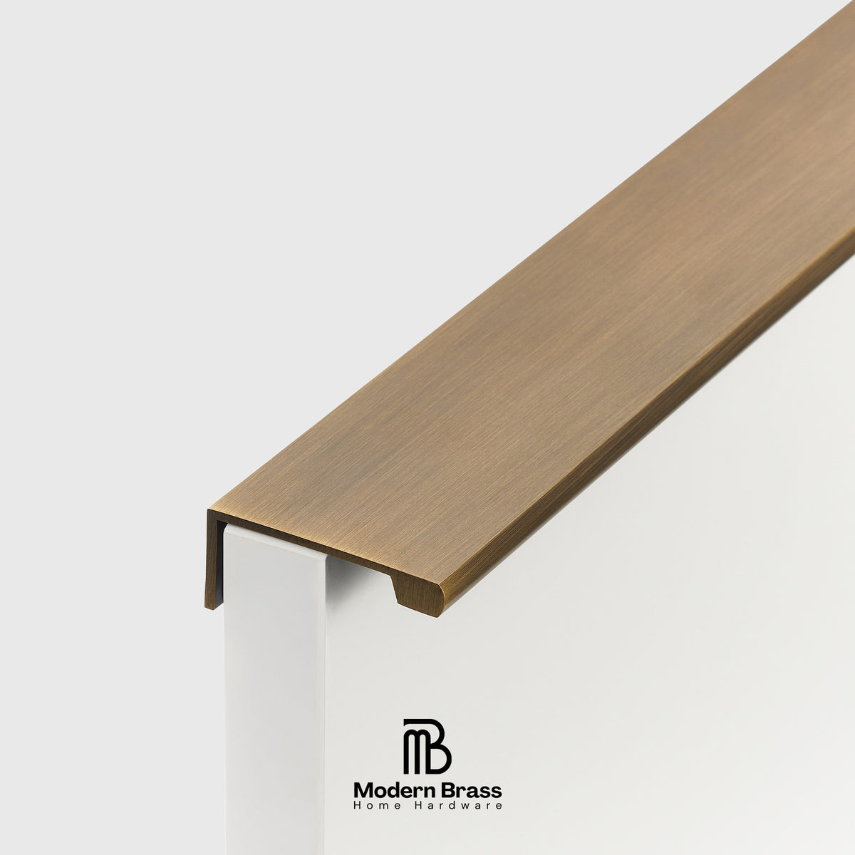 A close-up of a brushed brass stair rail profile with a white support post, featuring the Modern Brass Home Hardware logo at the bottom.