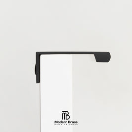 Three round cabinet knobs in black, matte brass, and brushed brass are arranged on a light beige surface against a warm beige background. The Modern Brass logo is visible at the bottom.