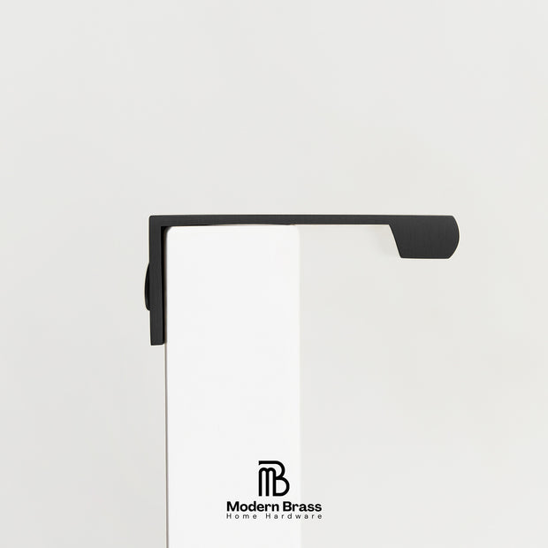 Three round cabinet knobs in black, matte brass, and brushed brass are arranged on a light beige surface against a warm beige background. The Modern Brass logo is visible at the bottom.