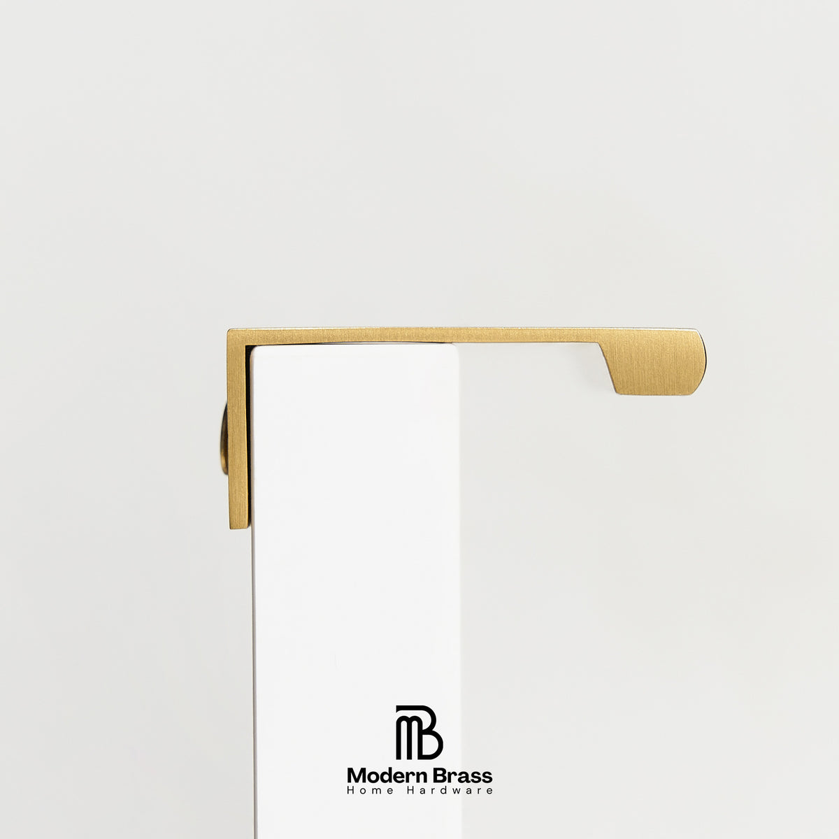 A close-up of a brass door handle mounted on a white door, with the Modern Brass logo printed at the bottom.
