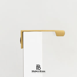 A close-up of a brass door handle mounted on a white door, with the Modern Brass logo printed at the bottom.