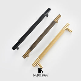Three round cabinet knobs in black, matte brass, and brushed brass are arranged on a light beige surface against a warm beige background. The Modern Brass logo is visible at the bottom.
