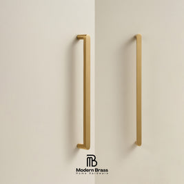 Two modern vertical brass cabinet handles mounted on a light beige wall, with the Modern Brass logo at the bottom.