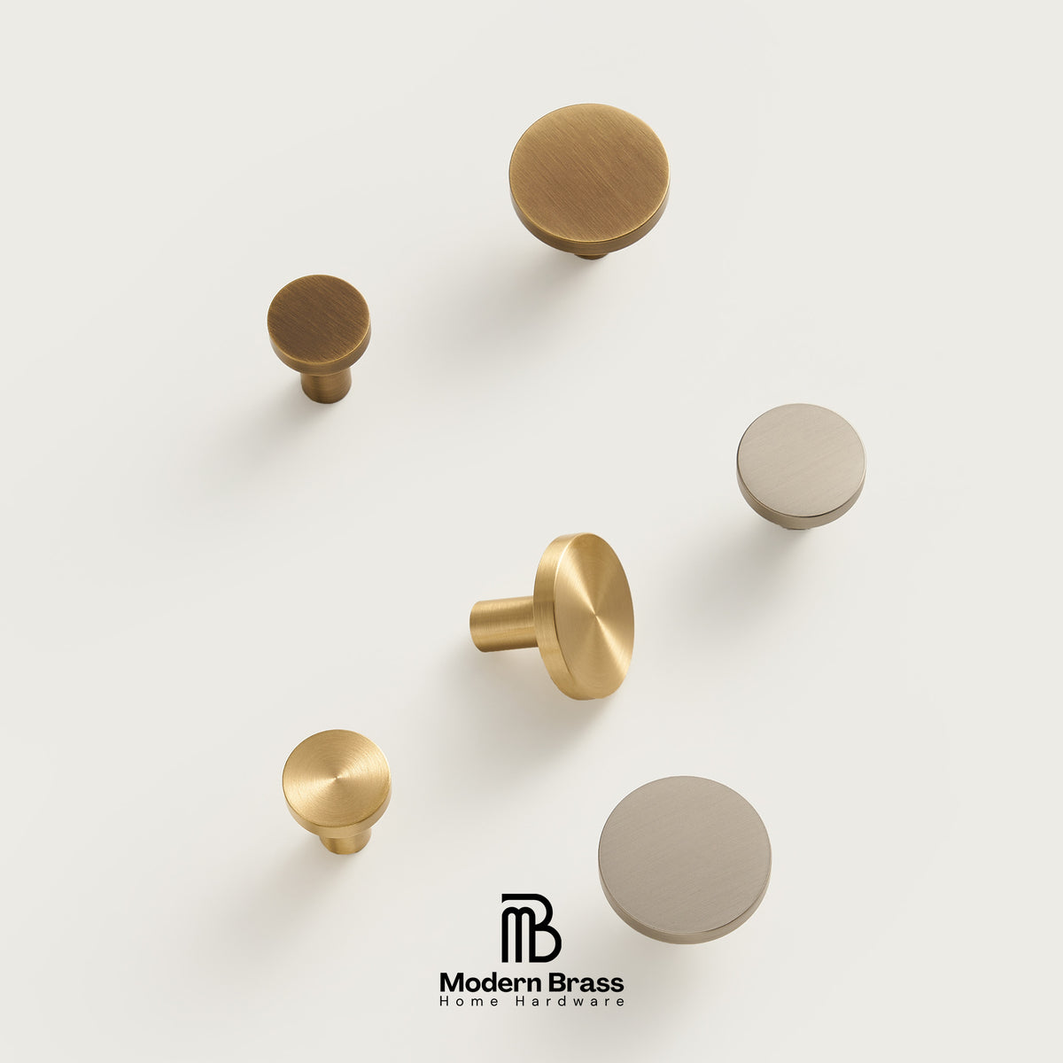 Three round cabinet knobs in black, matte brass, and brushed brass are arranged on a light beige surface against a warm beige background. The Modern Brass logo is visible at the bottom.