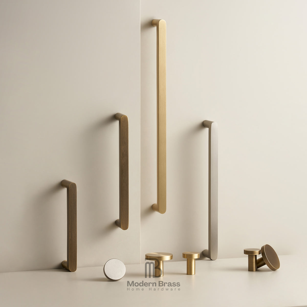 A collection of matte brass and brushed nickel modern cabinet handles in various shapes and sizes, displayed on a clean, light beige wall and surface with the Modern Brass logo at the bottom.