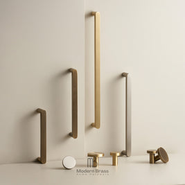 A collection of matte brass and brushed nickel modern cabinet handles in various shapes and sizes, displayed on a clean, light beige wall and surface with the Modern Brass logo at the bottom.