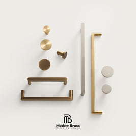 A set of modern brass home hardware pieces, including knobs, pulls, and bar handles, arranged neatly on a clean off-white background with the Modern Brass logo at the bottom.