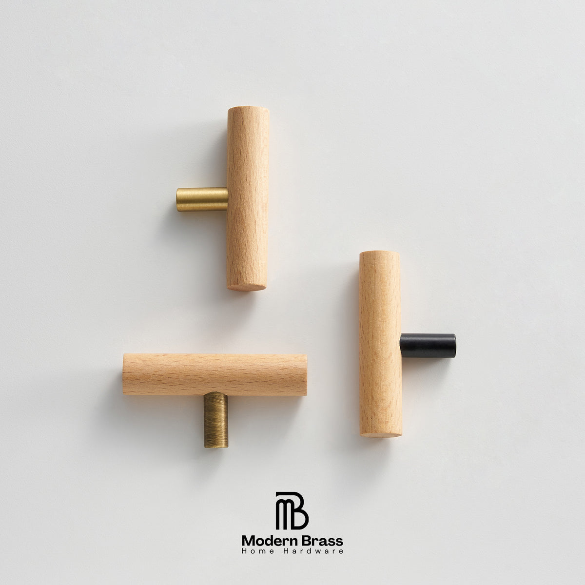 Three minimalist T-shaped wooden cabinet knobs with brass and black metal accents, arranged on a clean light gray background with the Modern Brass logo at the bottom.