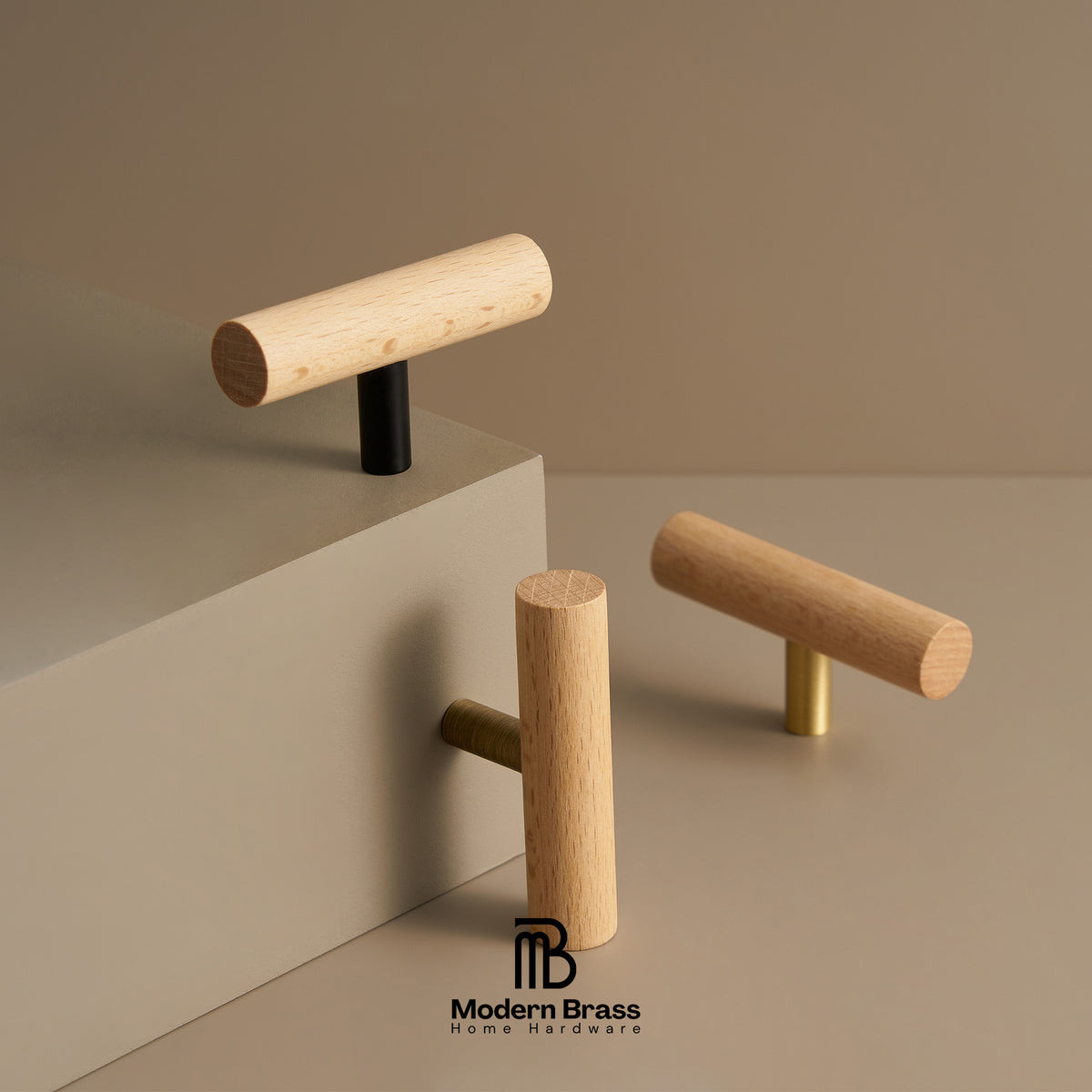 Three modern cylindrical wood cabinet knobs with different metal base accents (black, gold, and brass) displayed on a minimalist beige geometric set. The Modern Brass logo is visible at the bottom.